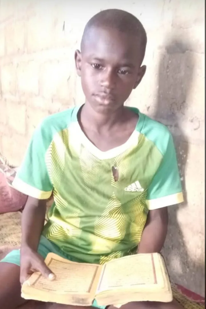 Mouhamed Nour All-Haqq enfant, assis sur une natte, lisant le Saint Coran